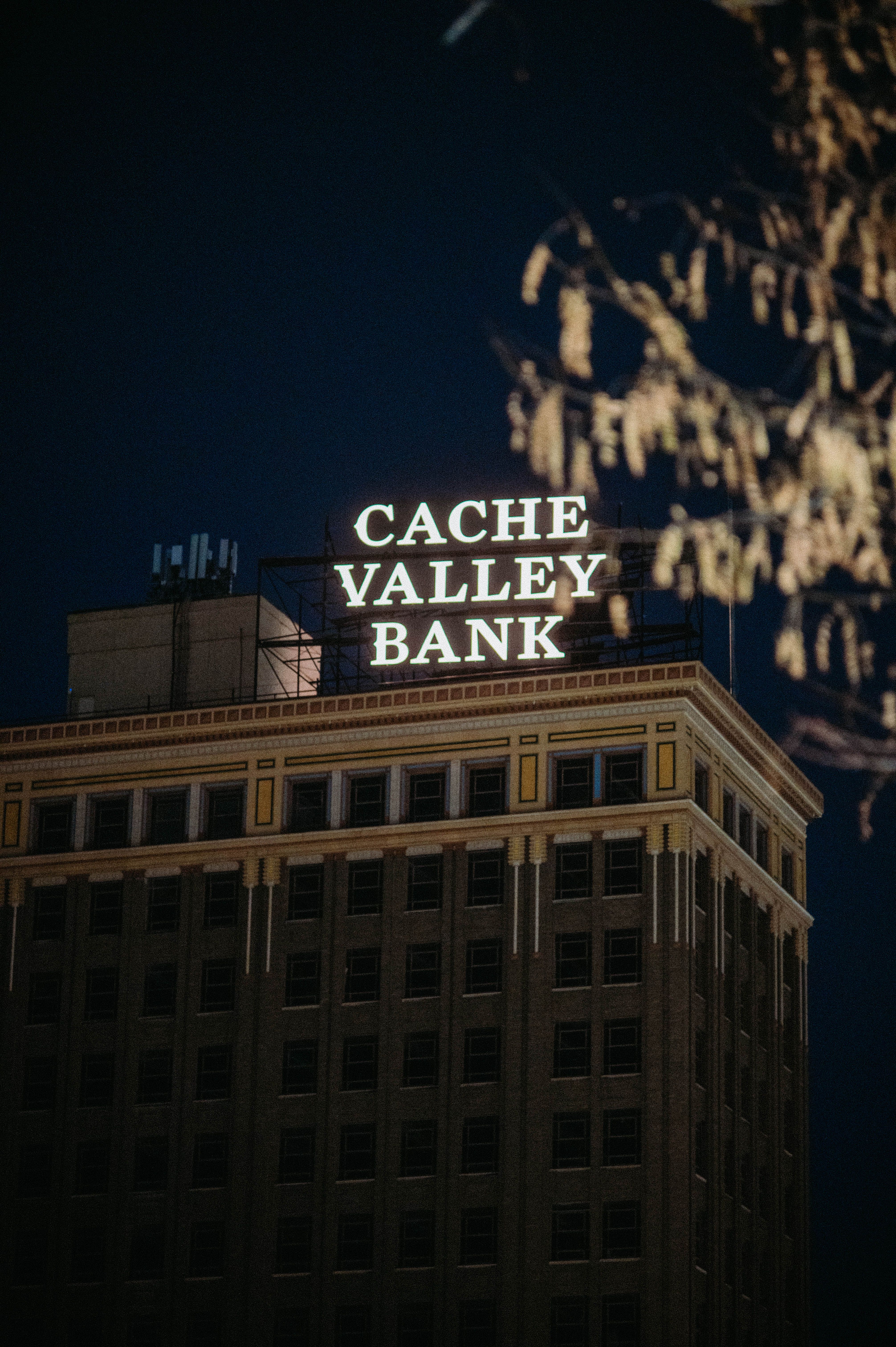 Night view of Cache Valley Bank building with distinctive neon signage, ideal for urban themes.