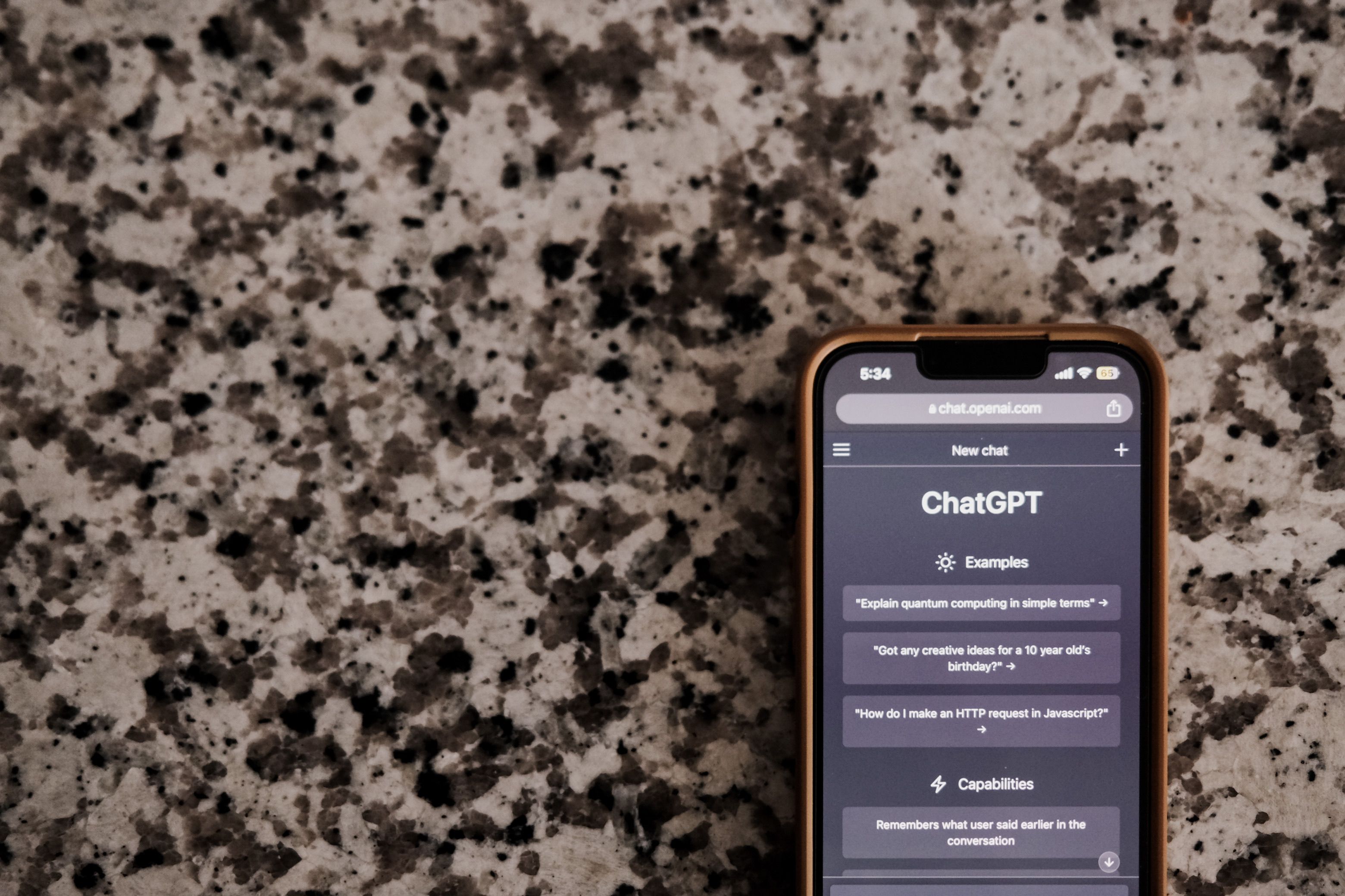 Close-up of a smartphone with ChatGPT interface on a speckled surface, highlighting technology and AI.