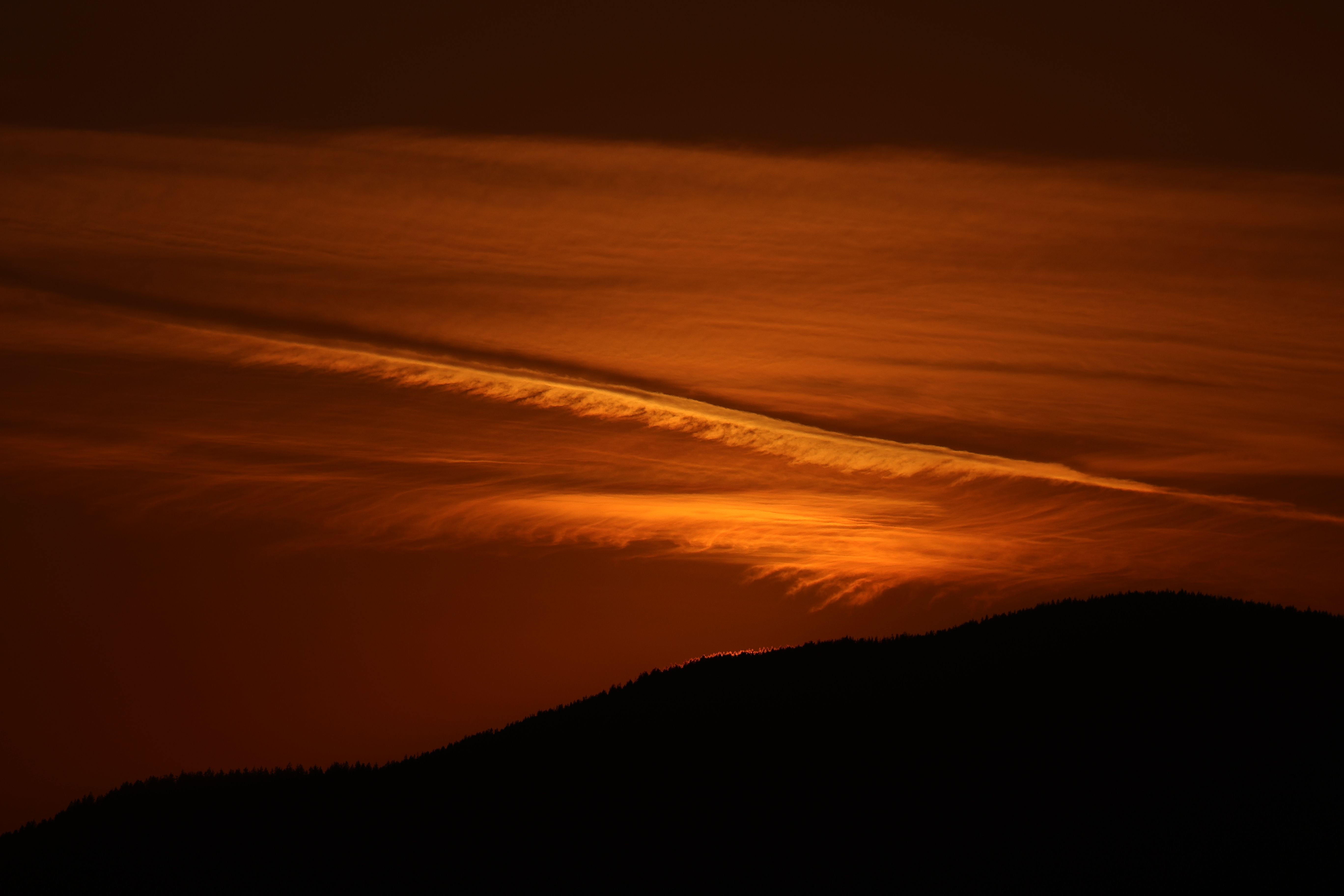 A vibrant sunset in Vancouver with striking orange clouds over silhouetted hills, perfect for atmospheric visuals.