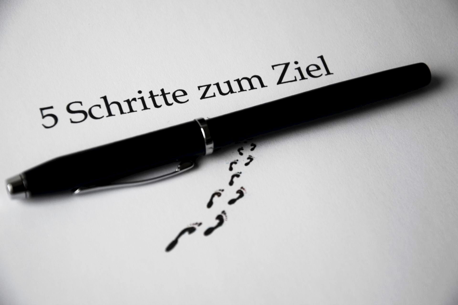 A black pen on a paper with text and footprint visual elements for a conceptual theme.