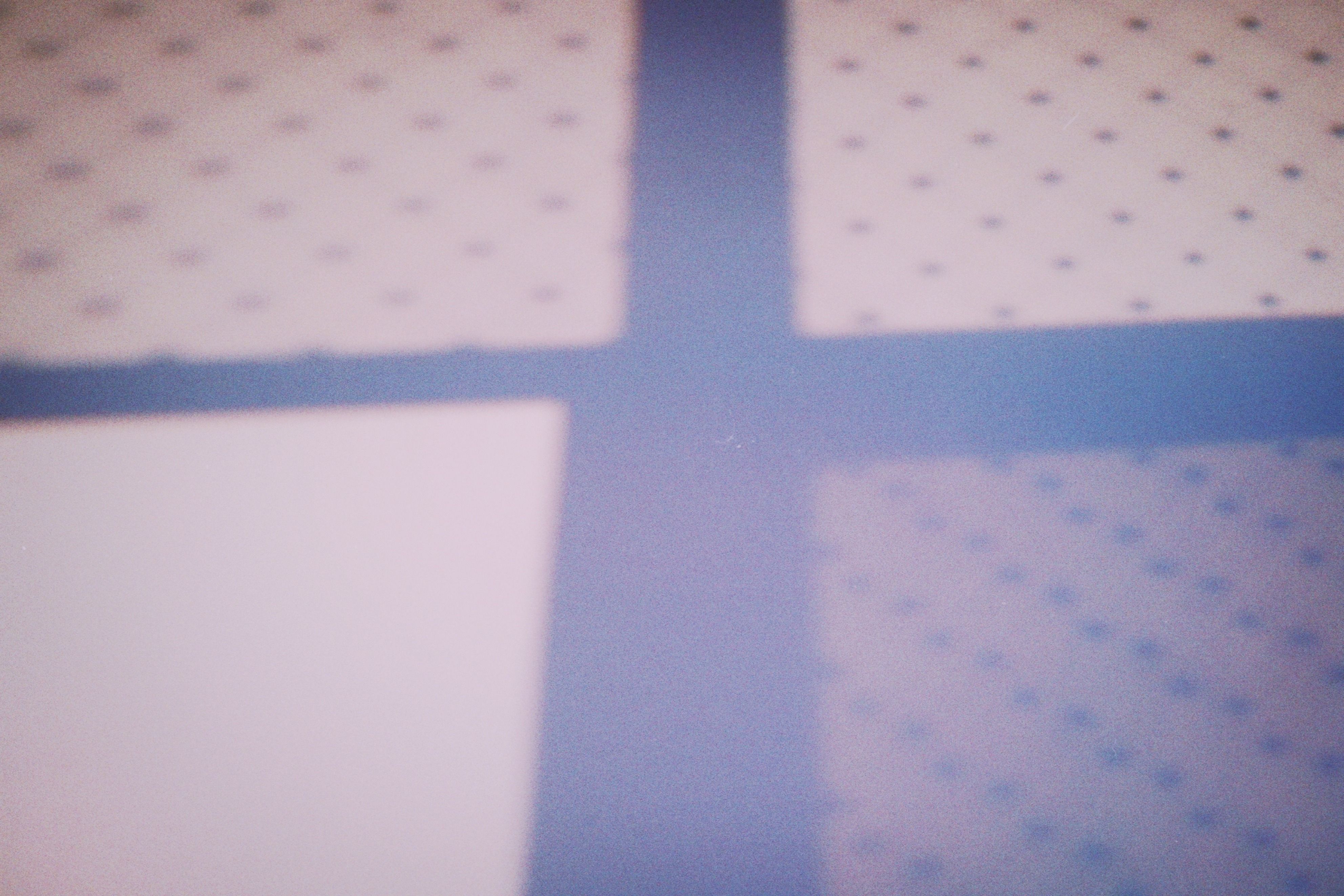 Abstract shadow forming a grid-like pattern on a dotted surface, creating a minimalist design aesthetic.