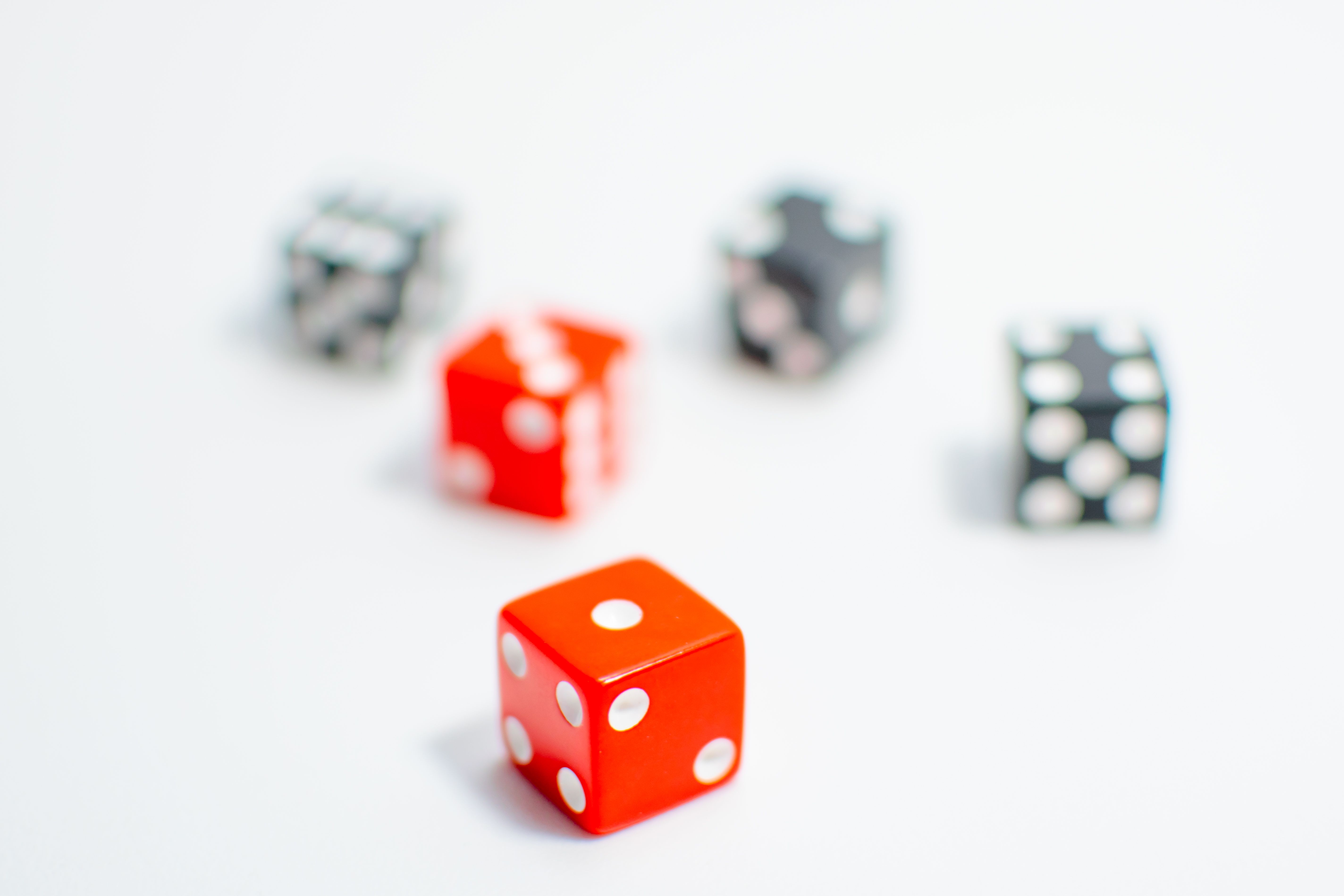 Vibrant red and black dice with white pips on a minimalist white surface, emphasizing focus.
