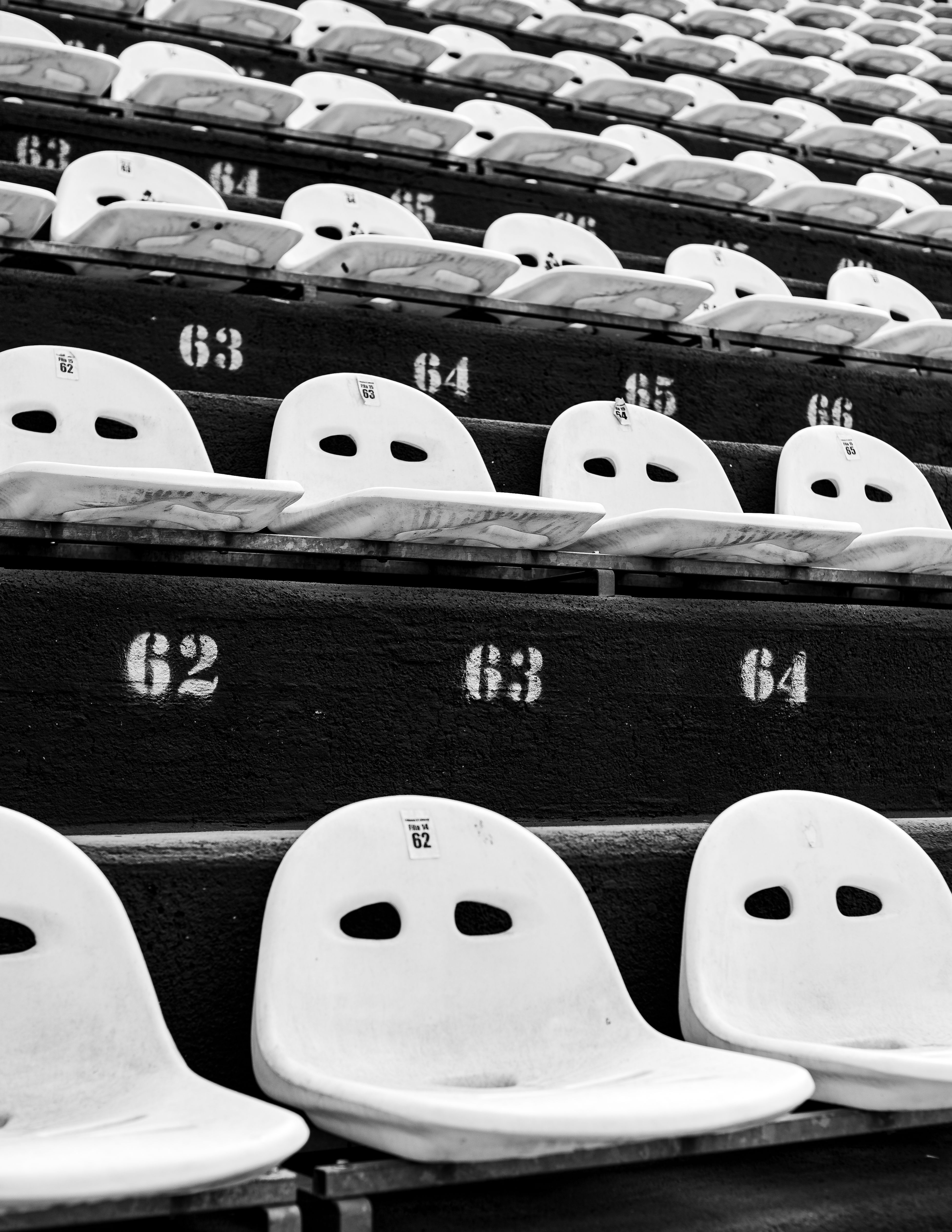 Abstract black and white photo of empty stadium seats showcasing seating arrangement and perspective.