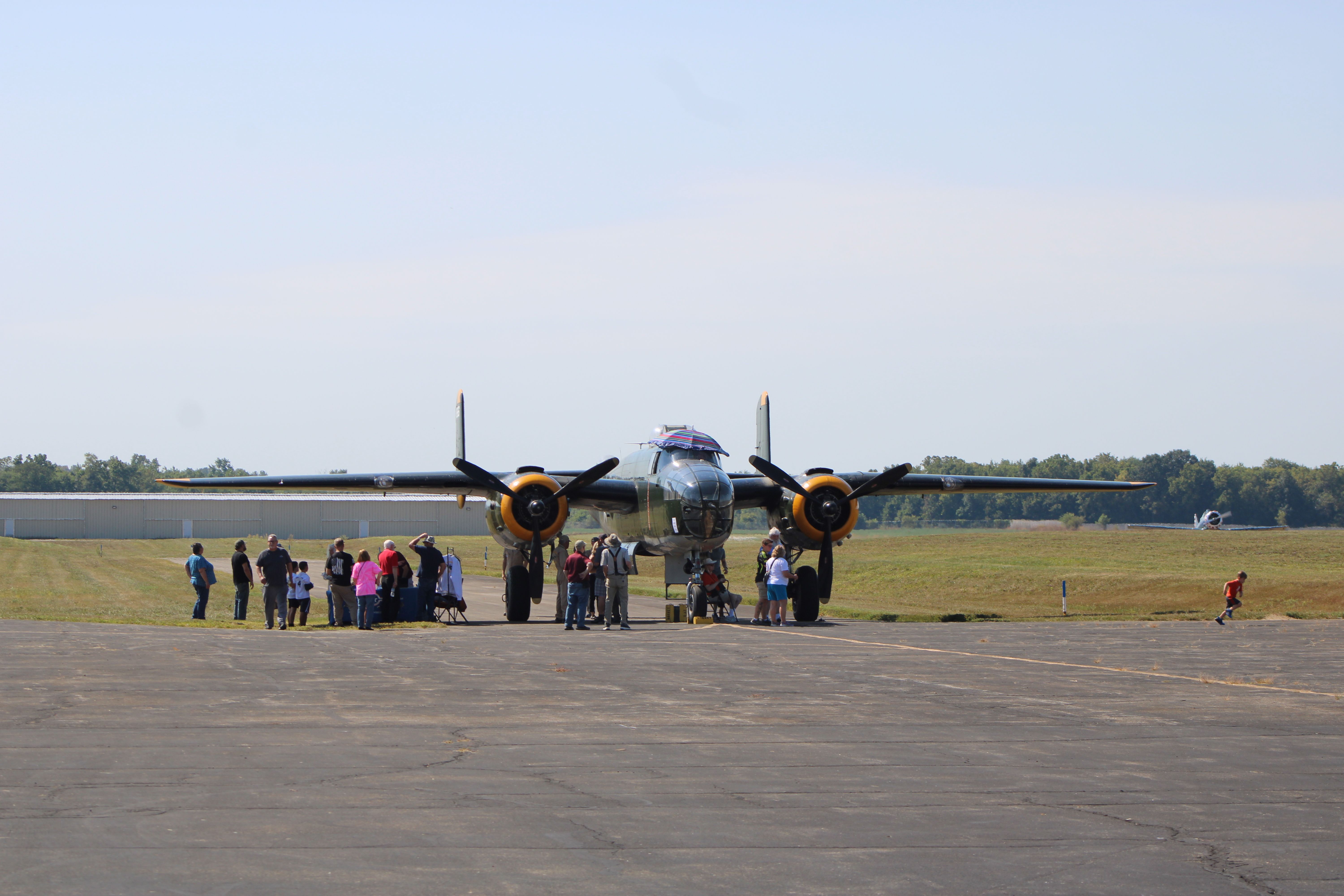 Front view of a vintage airplane with a group of people at Circleville Airport.