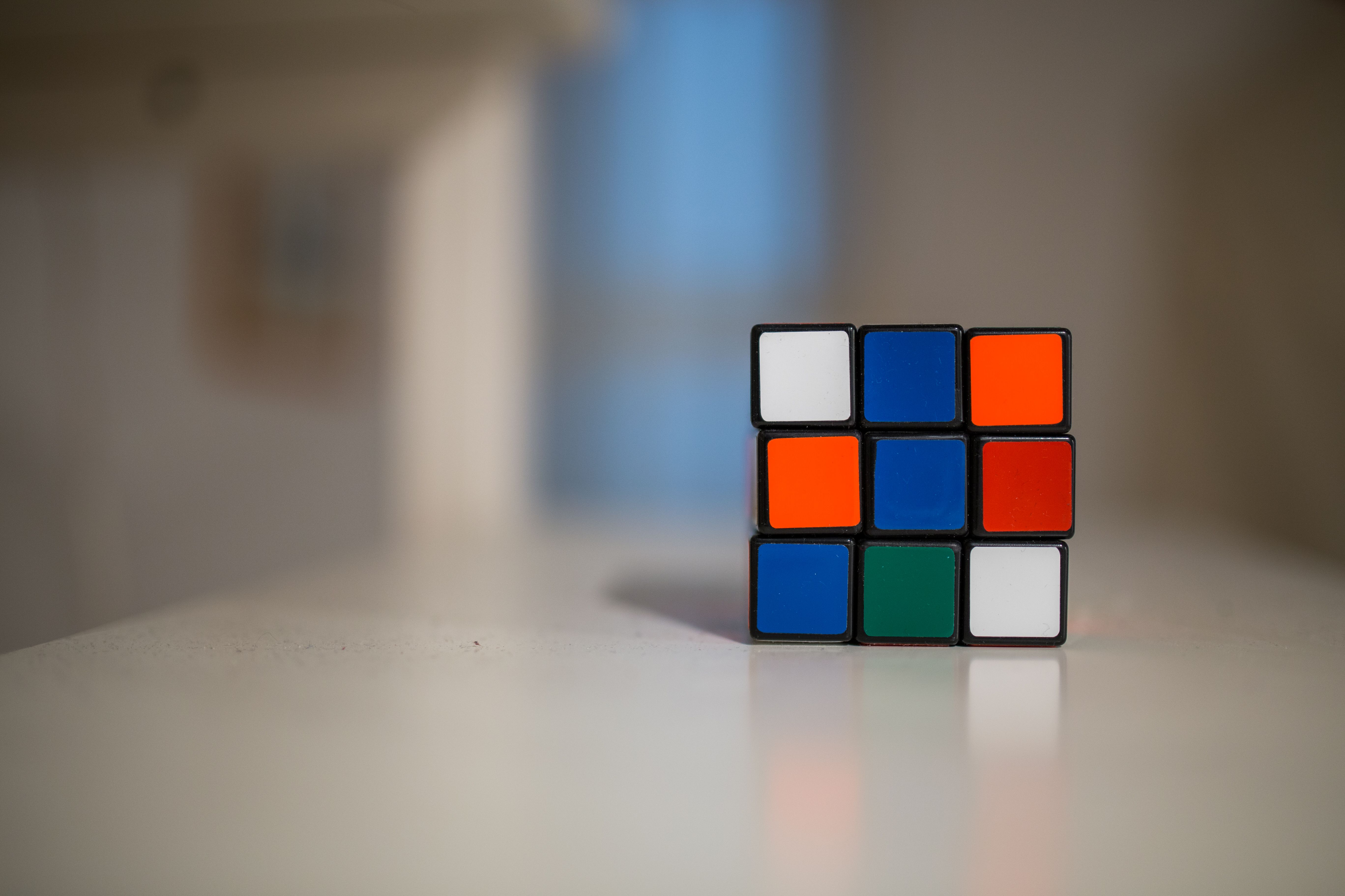 A close-up of a partially solved Rubik's Cube on a white table indoors.