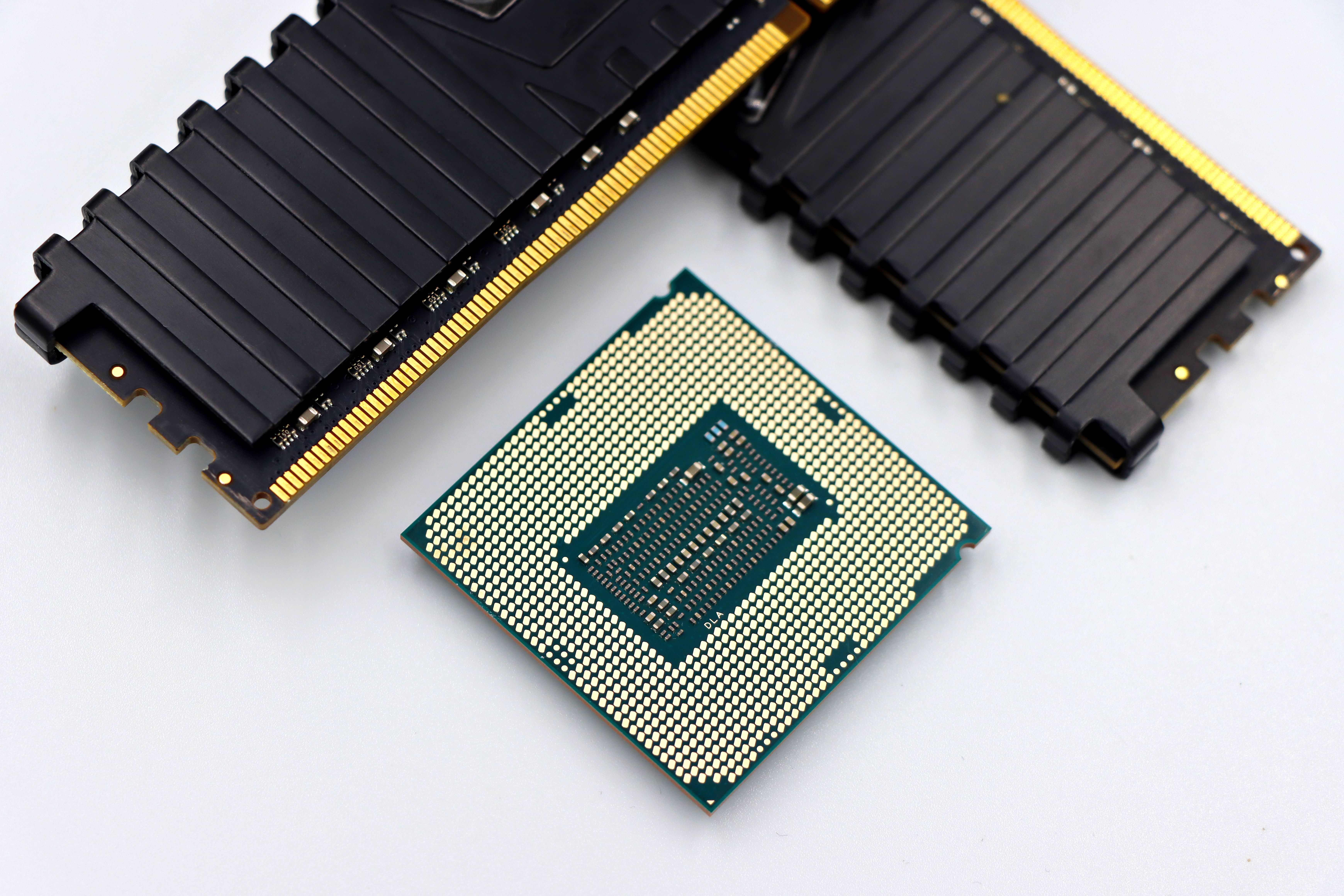 A CPU and RAM sticks displayed on a white surface, showcasing computer hardware components.