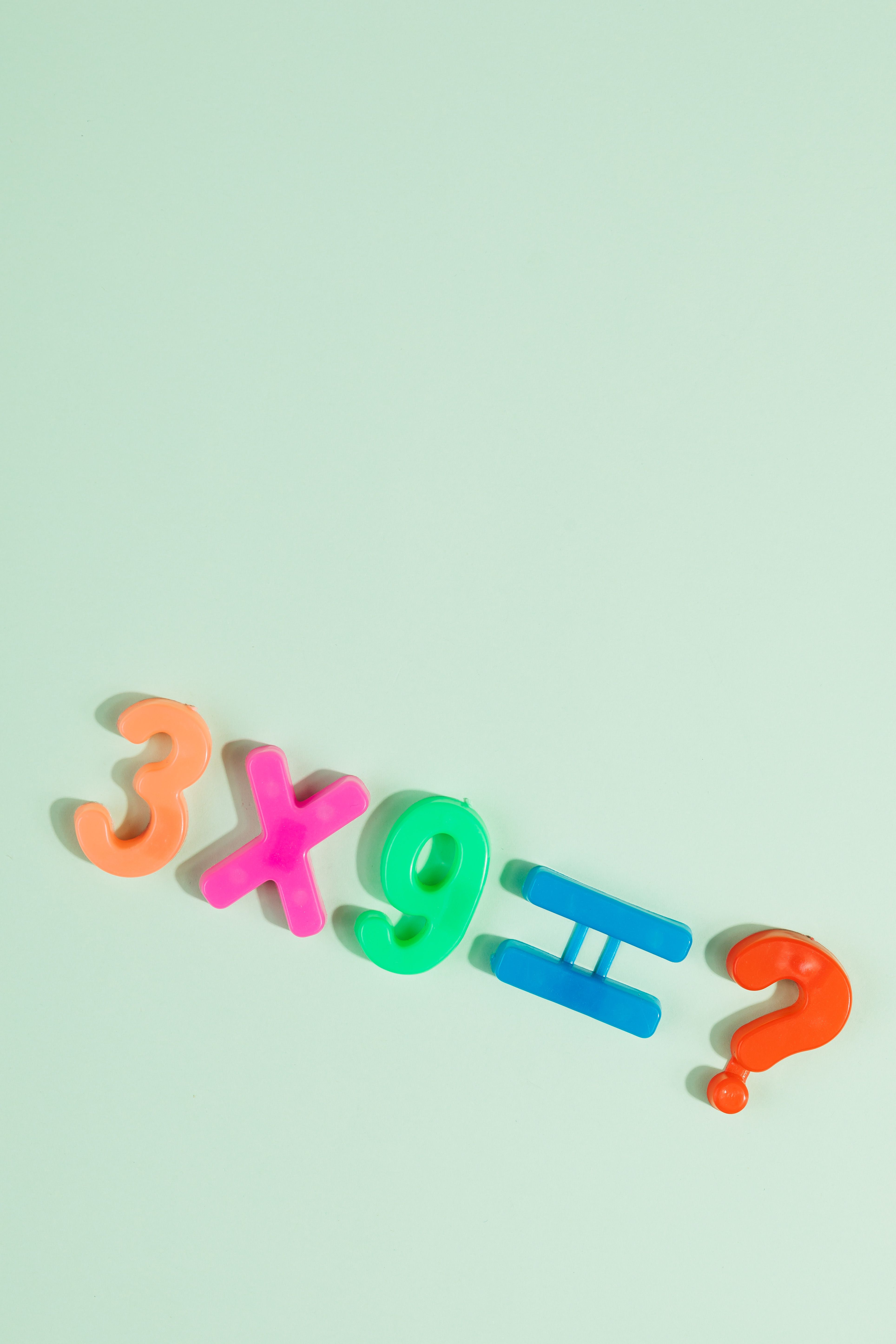 Bright numbers and symbols for multiplication equation on pastel green surface.