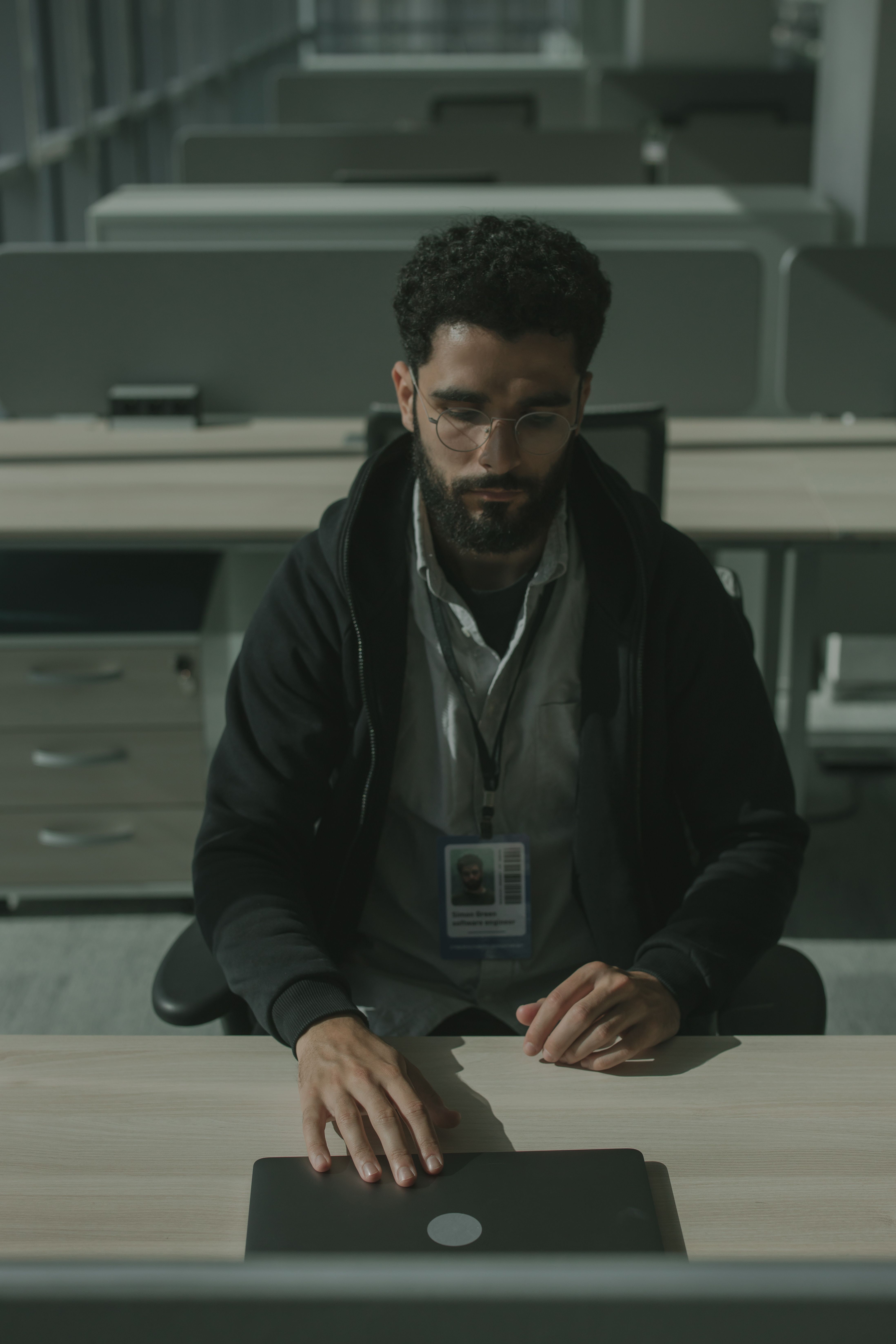 A serious software engineer working diligently in a dimly lit office setting.