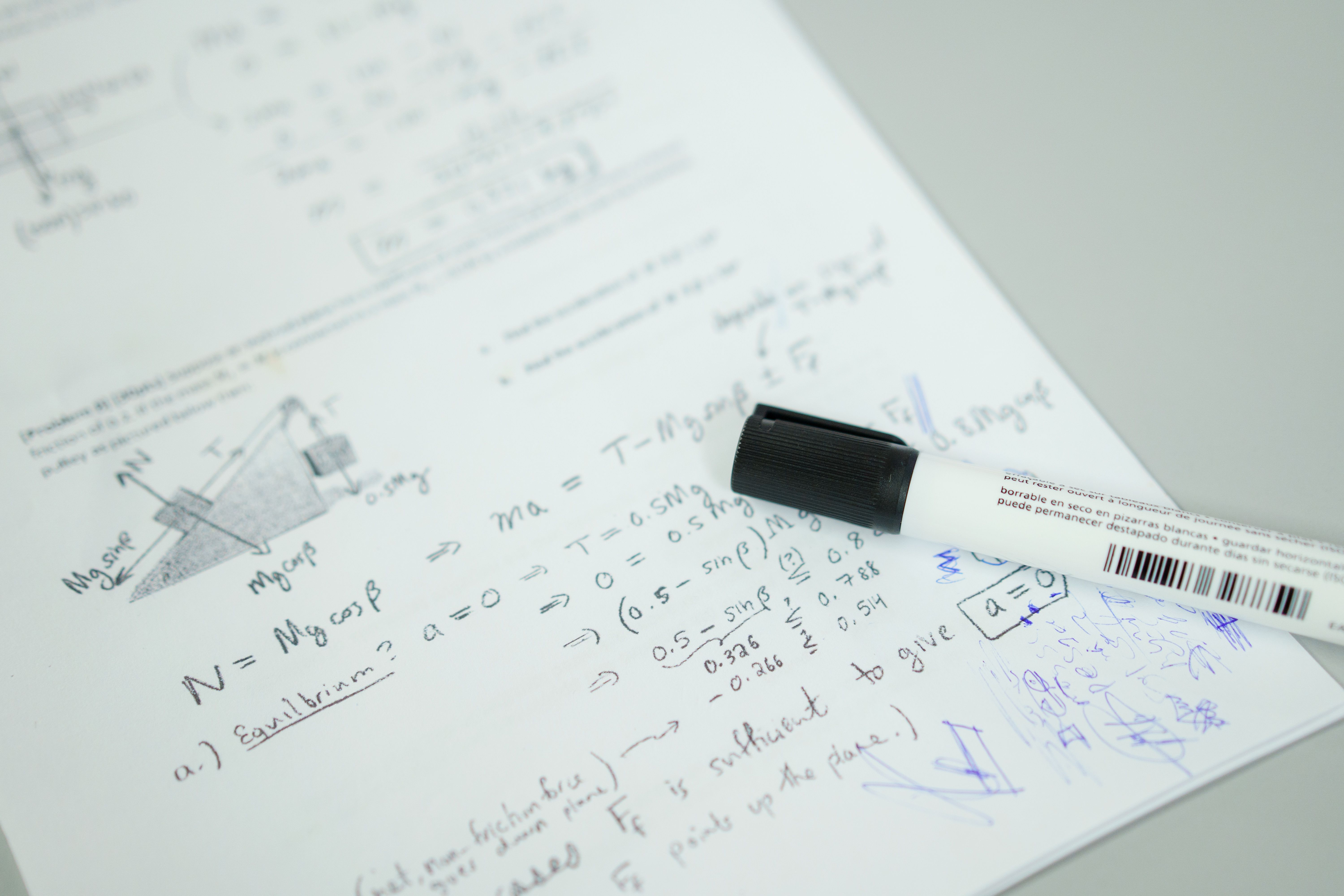 Close-up showing mathematical formulas and a marker on bond paper, ideal for education themes.