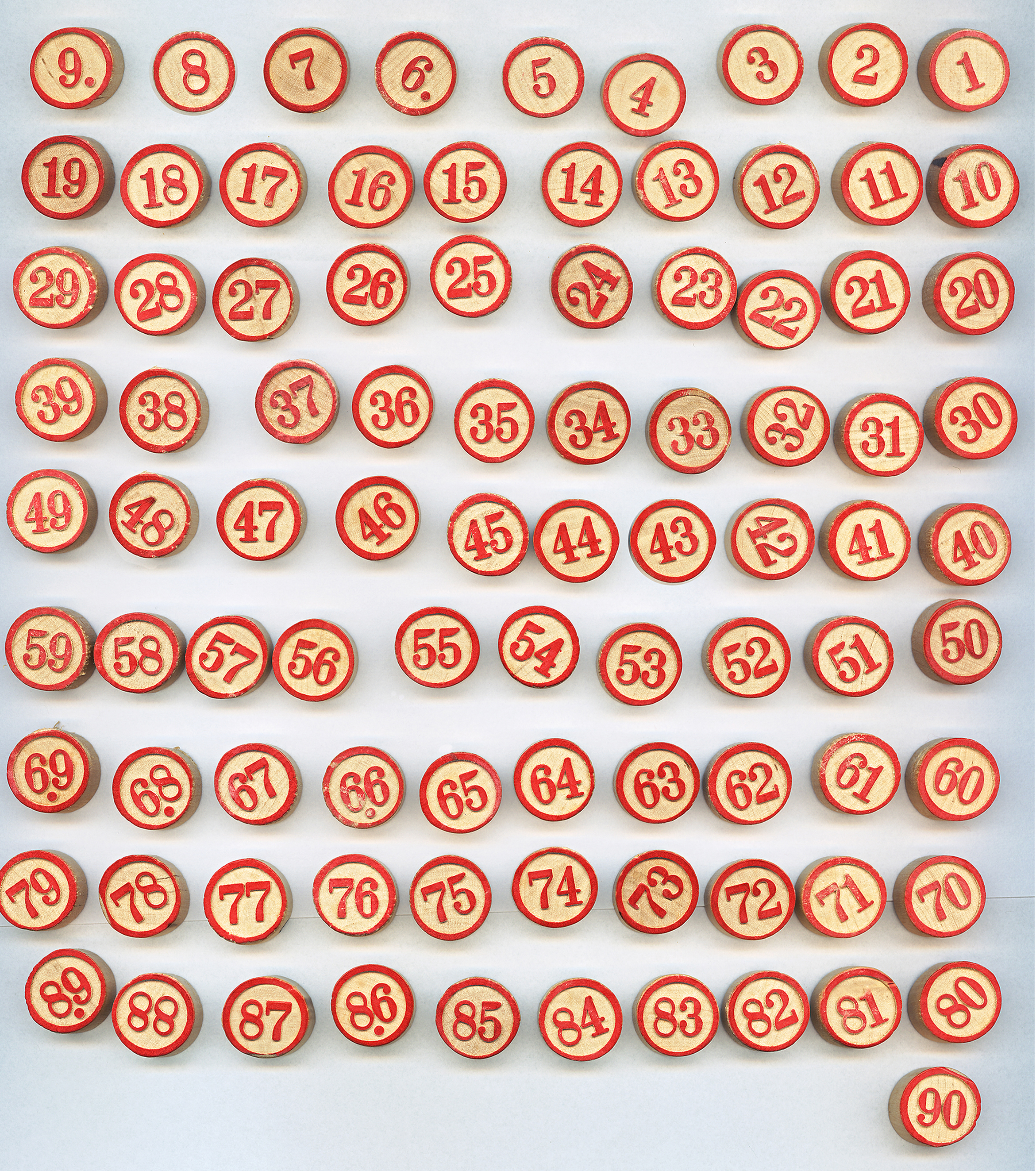 Red and wood bingo chips arranged in rows on a white surface, highlighting numbers.