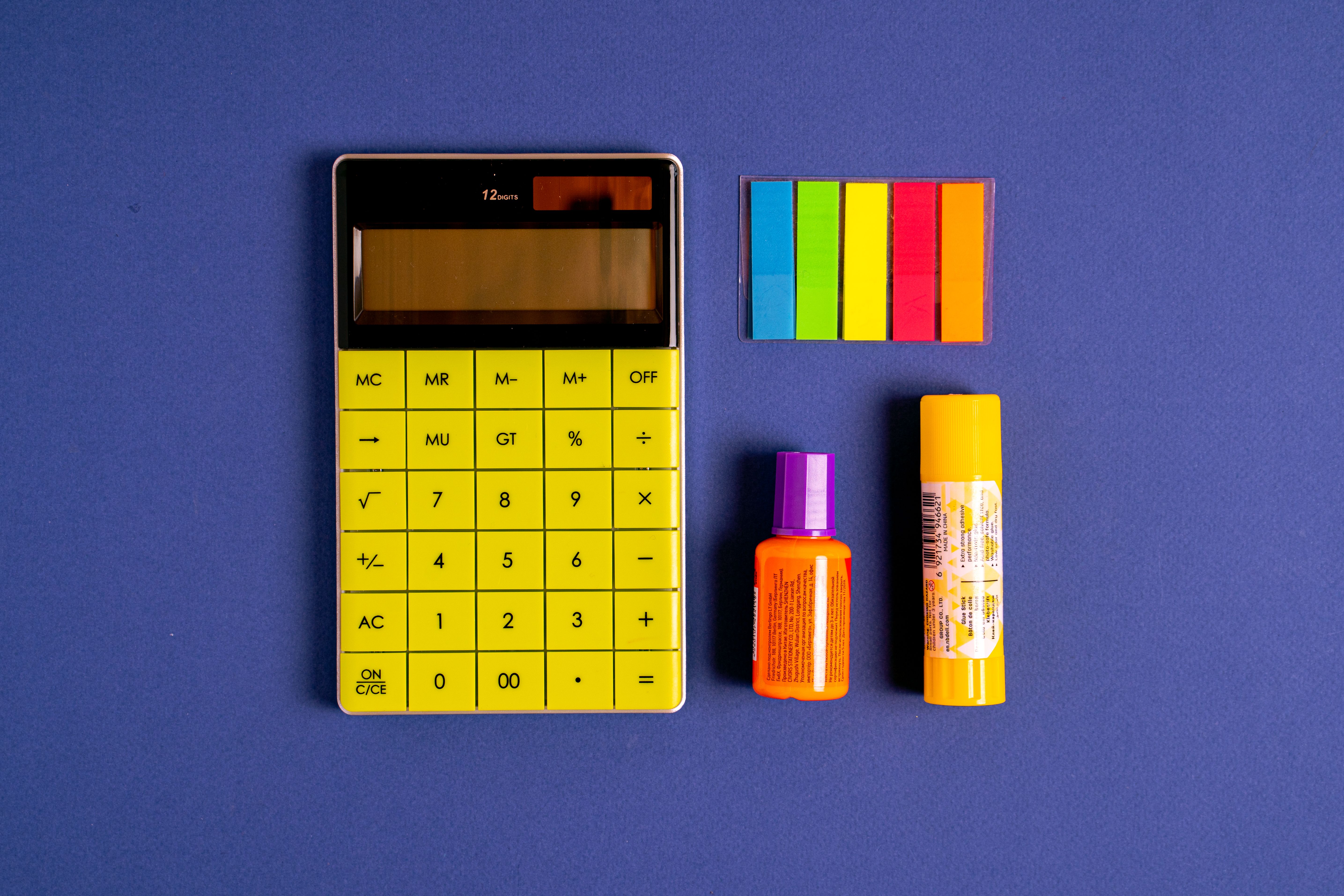 Bright office supplies including calculator and sticky notes on a vibrant blue surface.