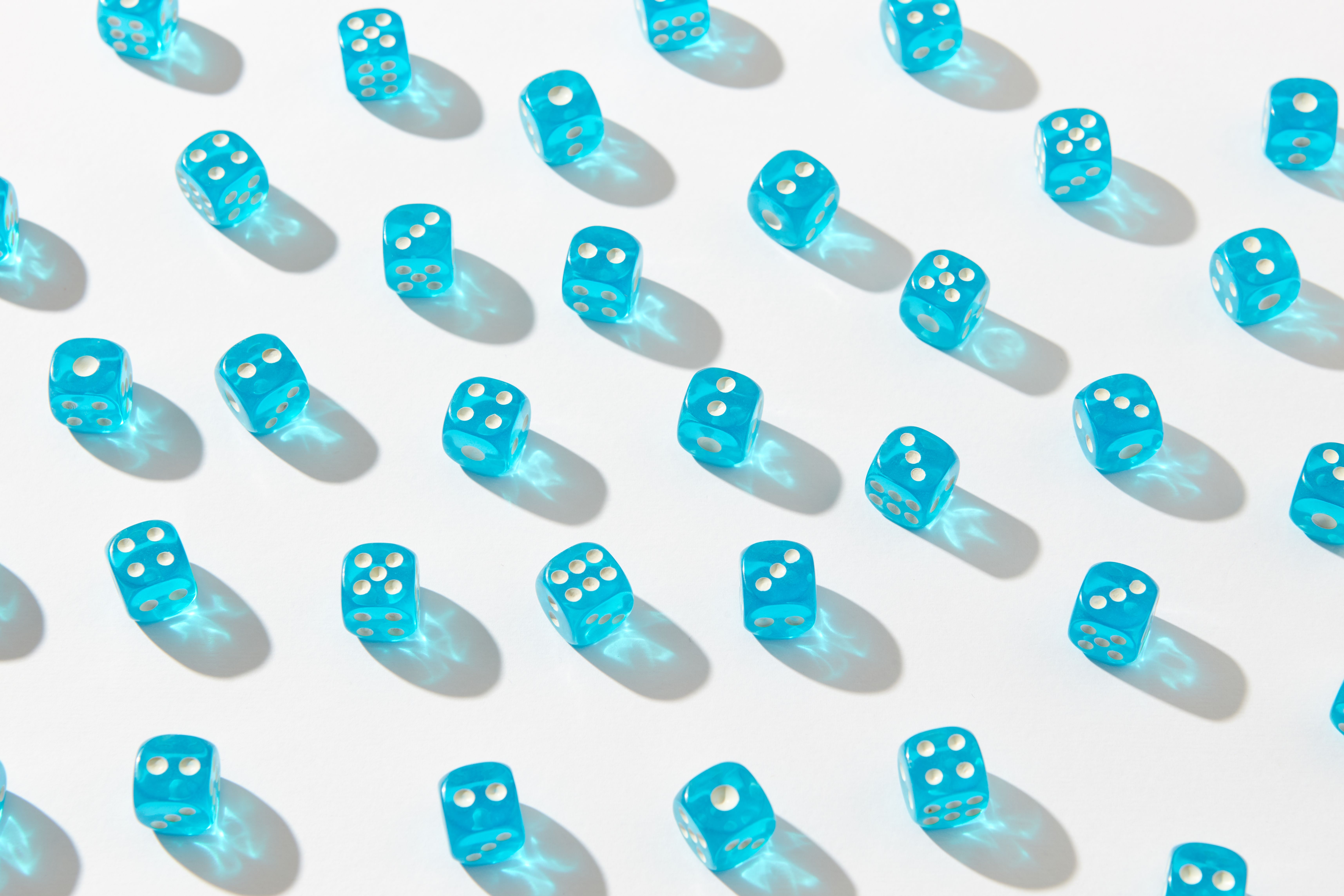 A captivating pattern of blue transparent dice casting shadows on a white surface.