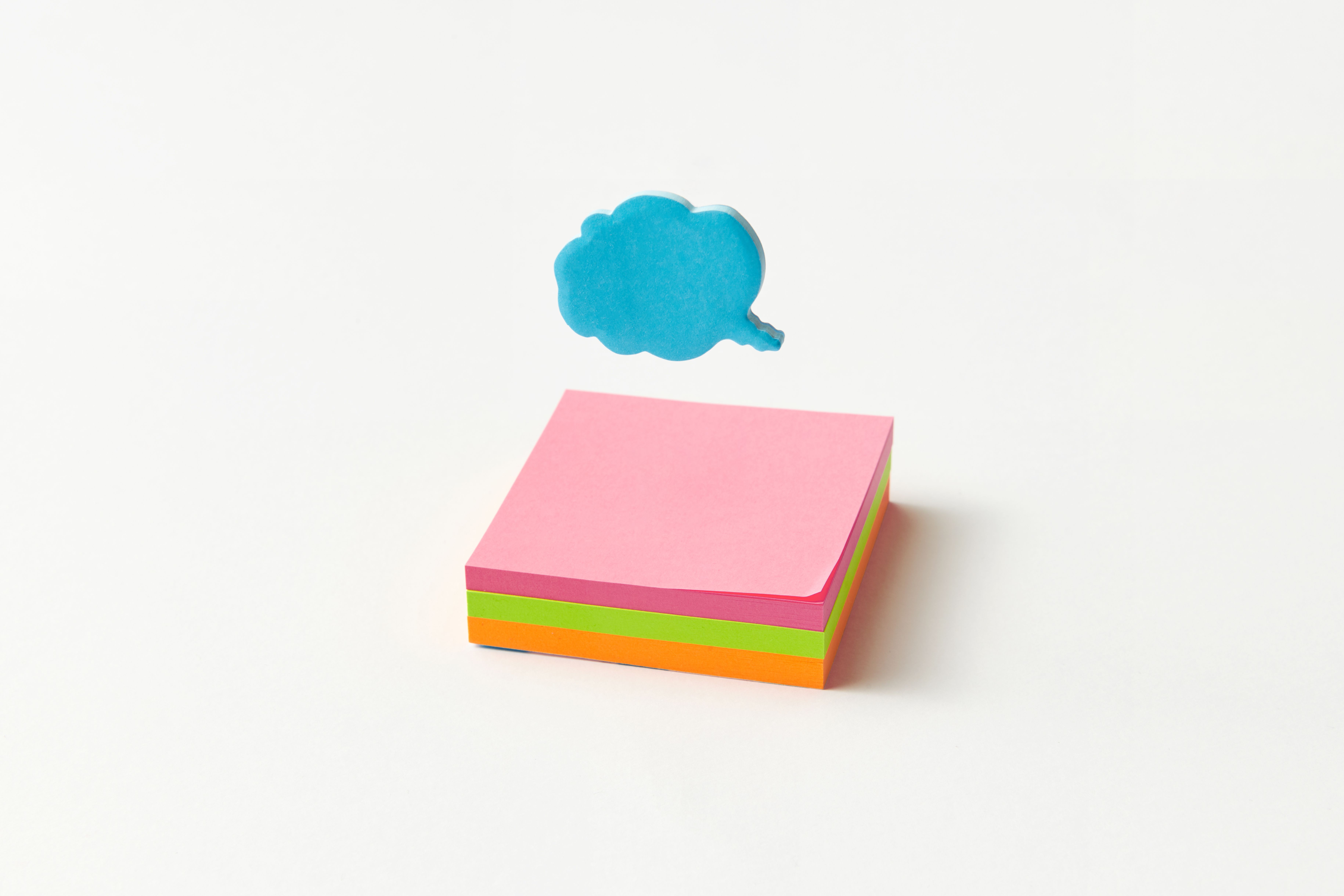 Vibrant stack of sticky notes with a blue cloud-shaped speech bubble on a white background.