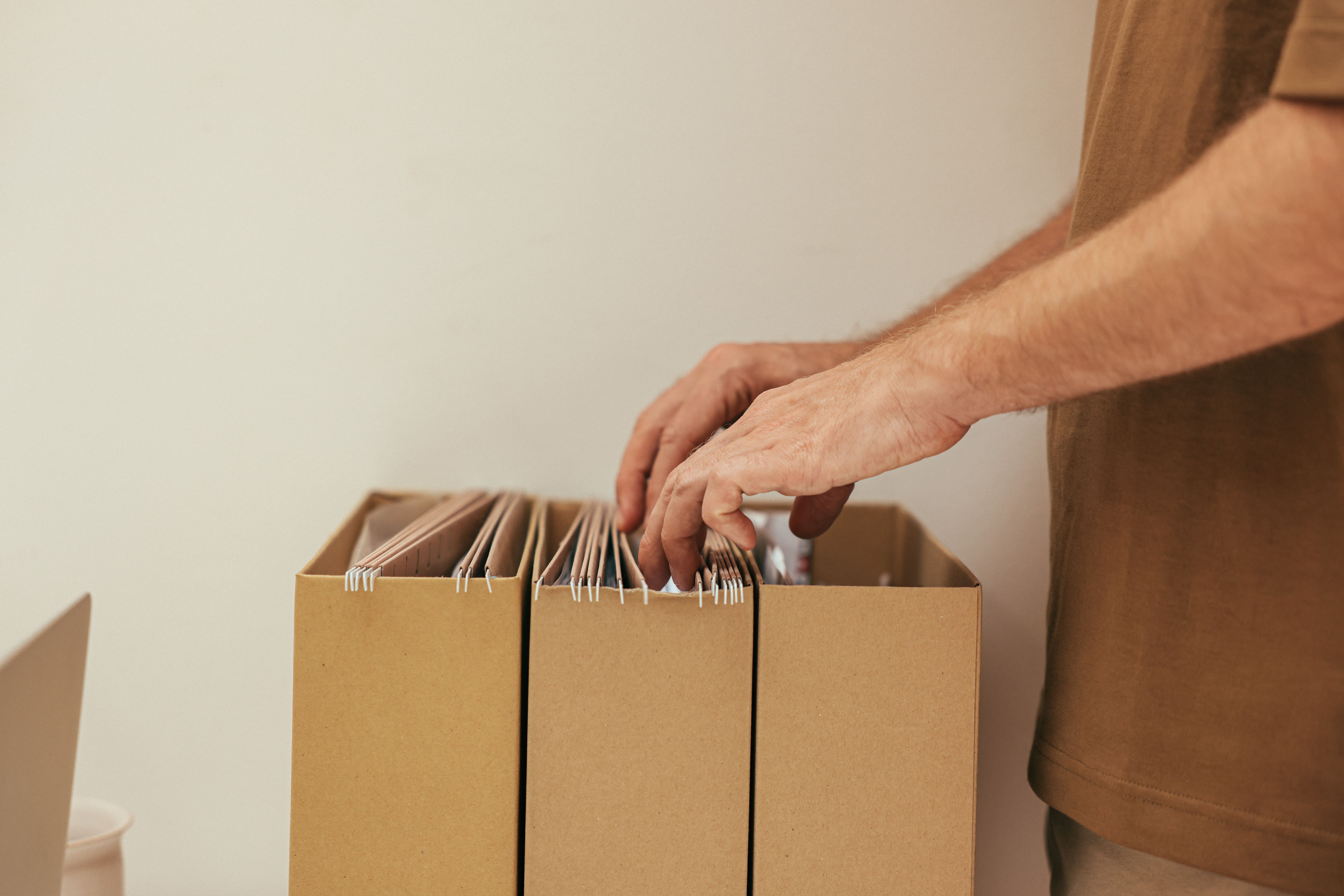 Close-up of a person organizing files in cardboard boxes, ideal for business and office themes.
