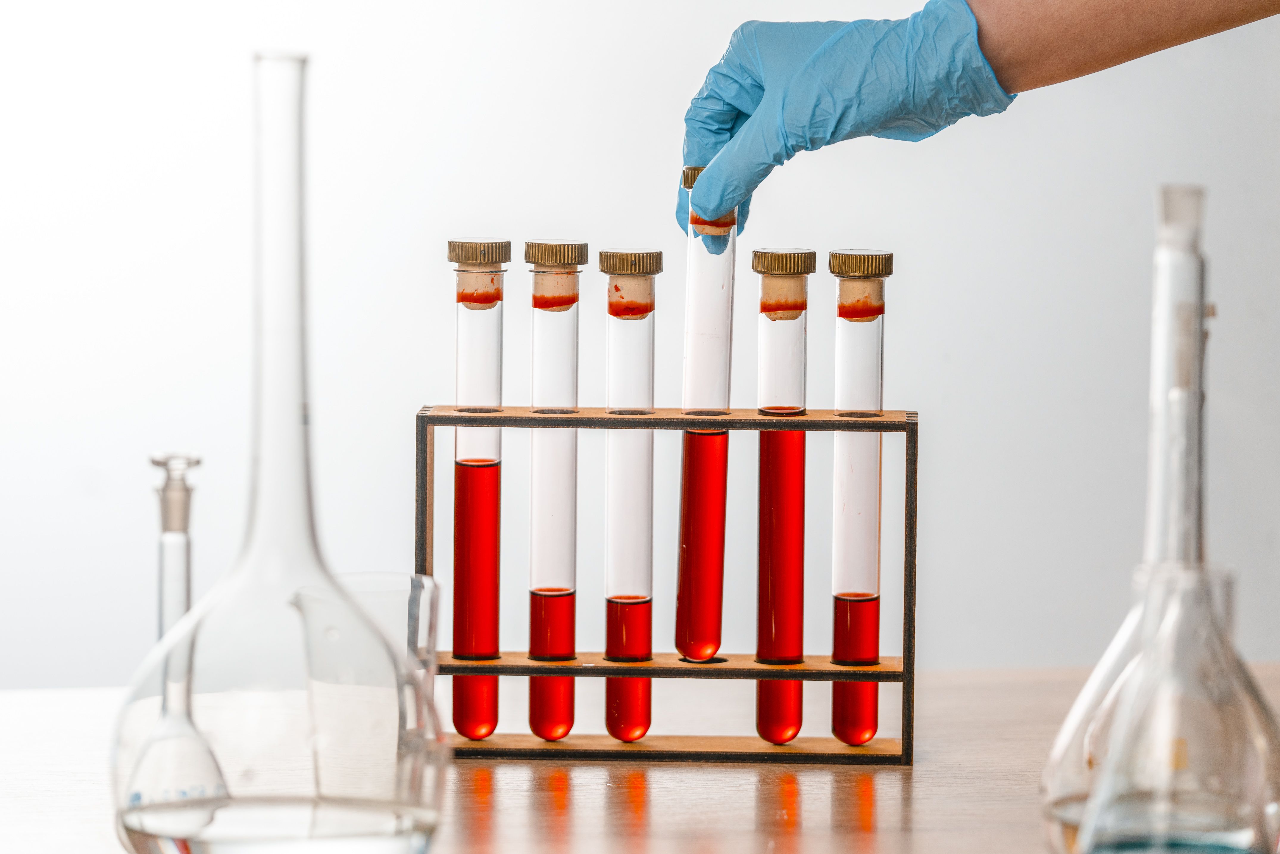 Close-up of gloved hand handling test tubes in a scientific laboratory setting.